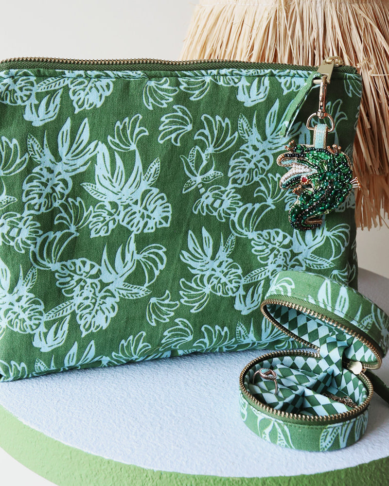 Green patterned cosmetic pouch with a decorative charm and mini linen jewellery box on a white surface