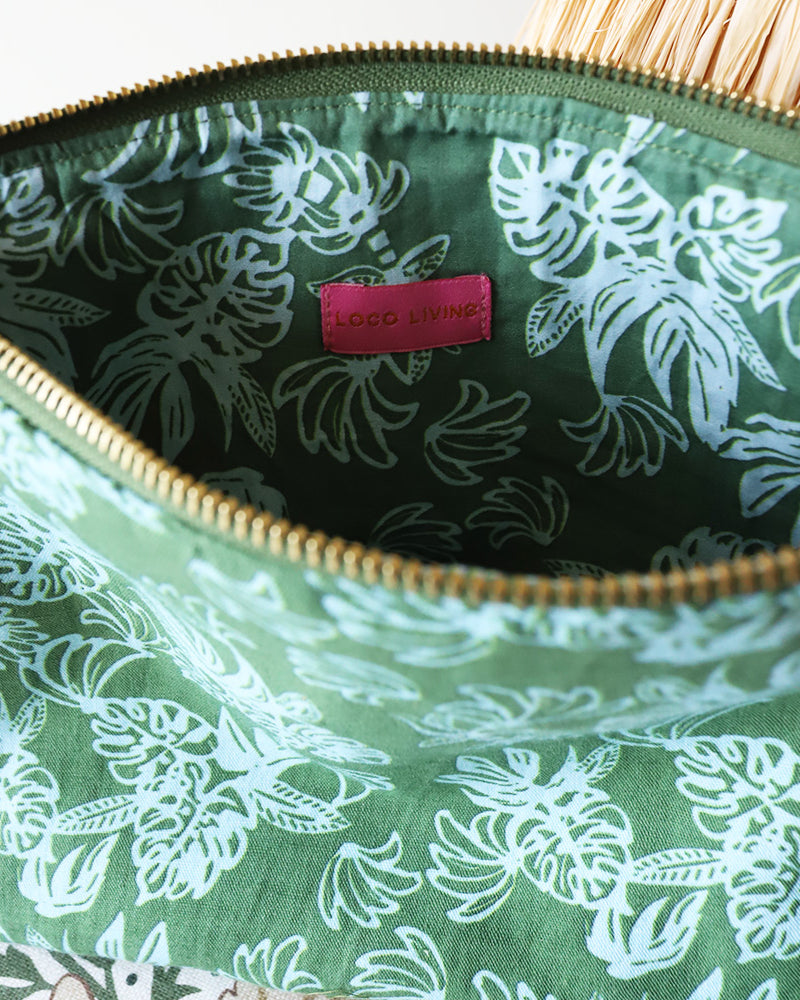 Green floral-patterned pouch with a pink label on a white background