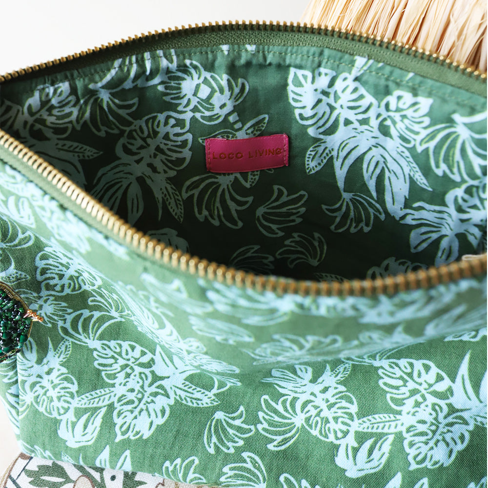 Green floral-patterned pouch with a pink label on a white background