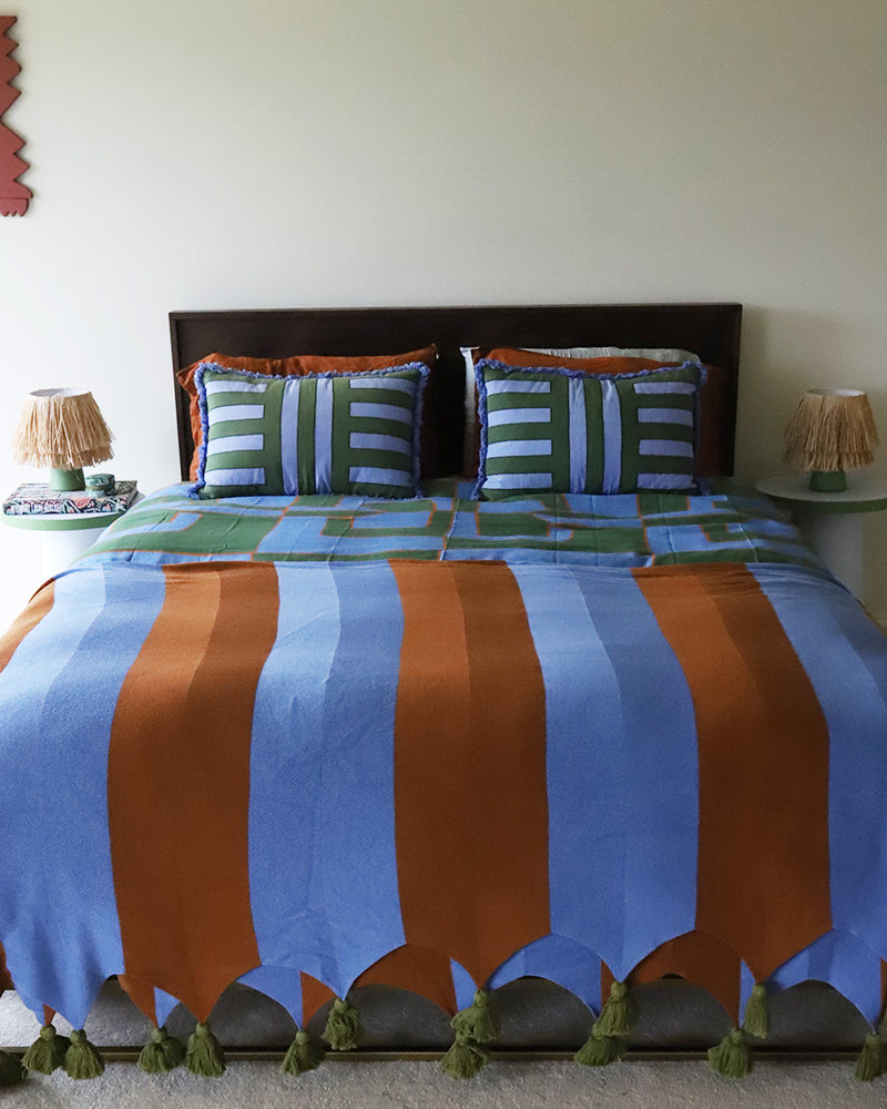 Bed with colorful striped throw blanket in brown and blue in a room setting