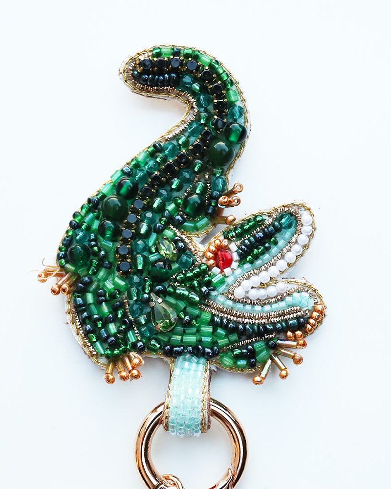 Decorative keychain with green beaded design on a white background