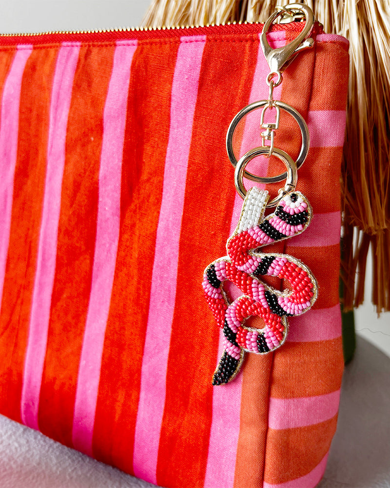 Red and pink striped pouch with a decorative snake beaded keychain on a white background