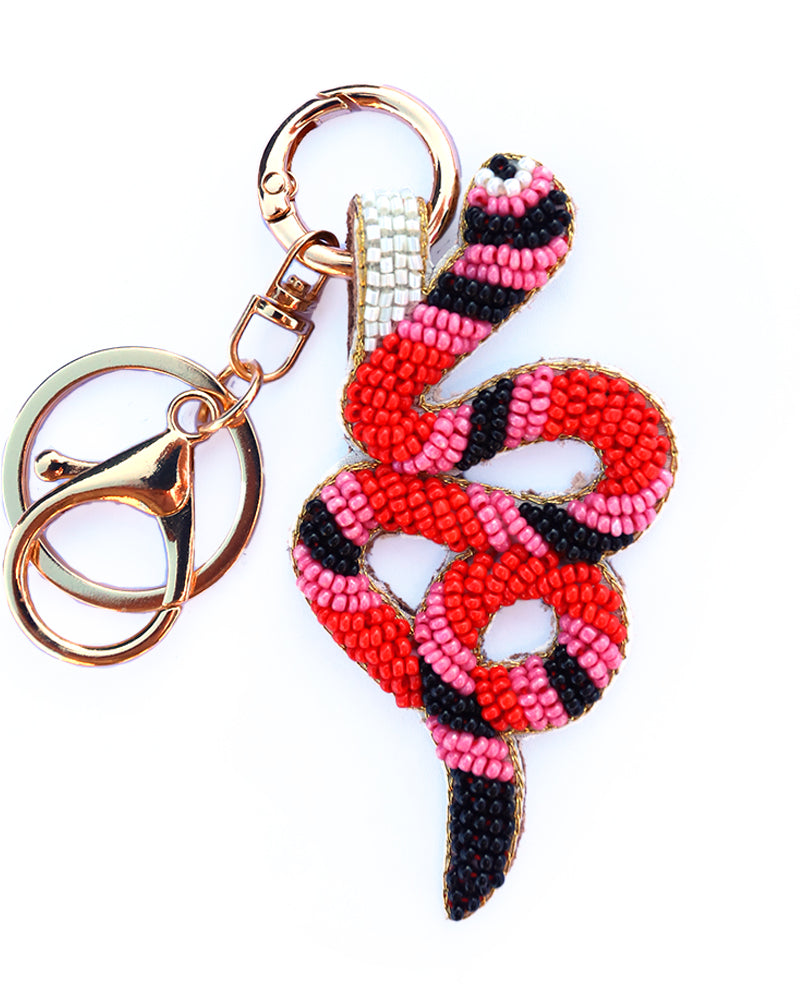 Snake-shaped beaded keychain with pink and black pattern on a white background