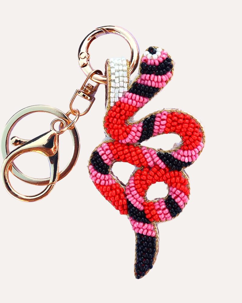 Snake-shaped beaded keychain with pink and black pattern on a white background