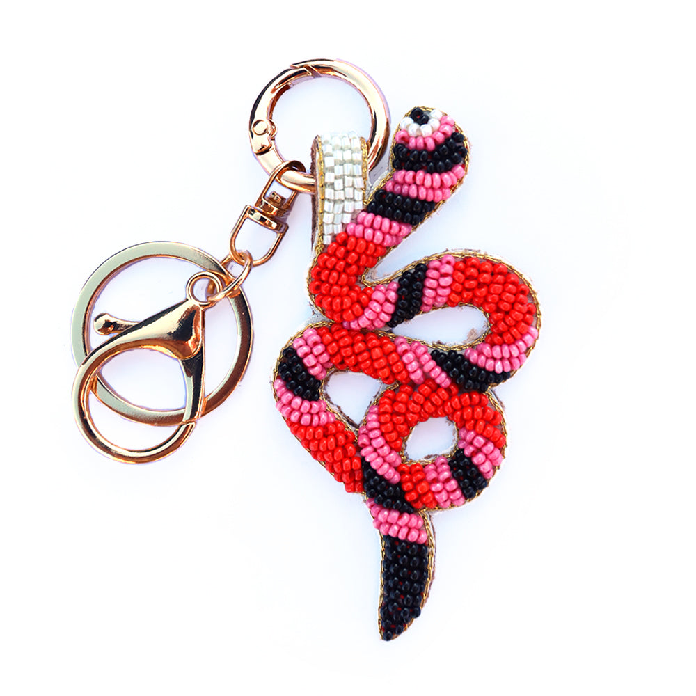 Snake-shaped beaded keychain with pink and black pattern on a white background