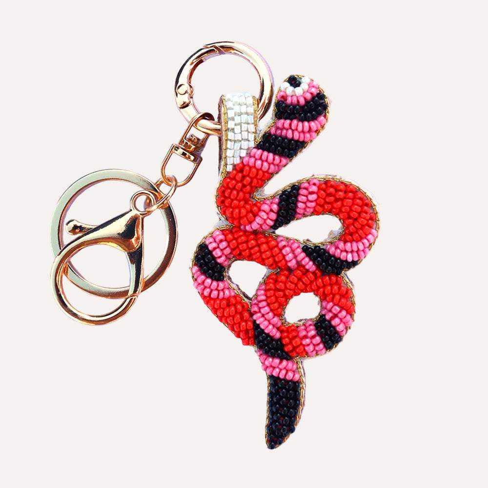 Snake-shaped beaded keychain with pink and black pattern on a white background