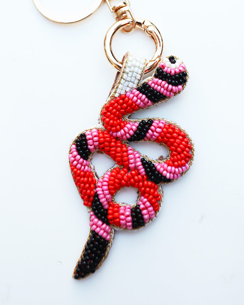 Snake-shaped keychain with red, pink, and black beads on a white background