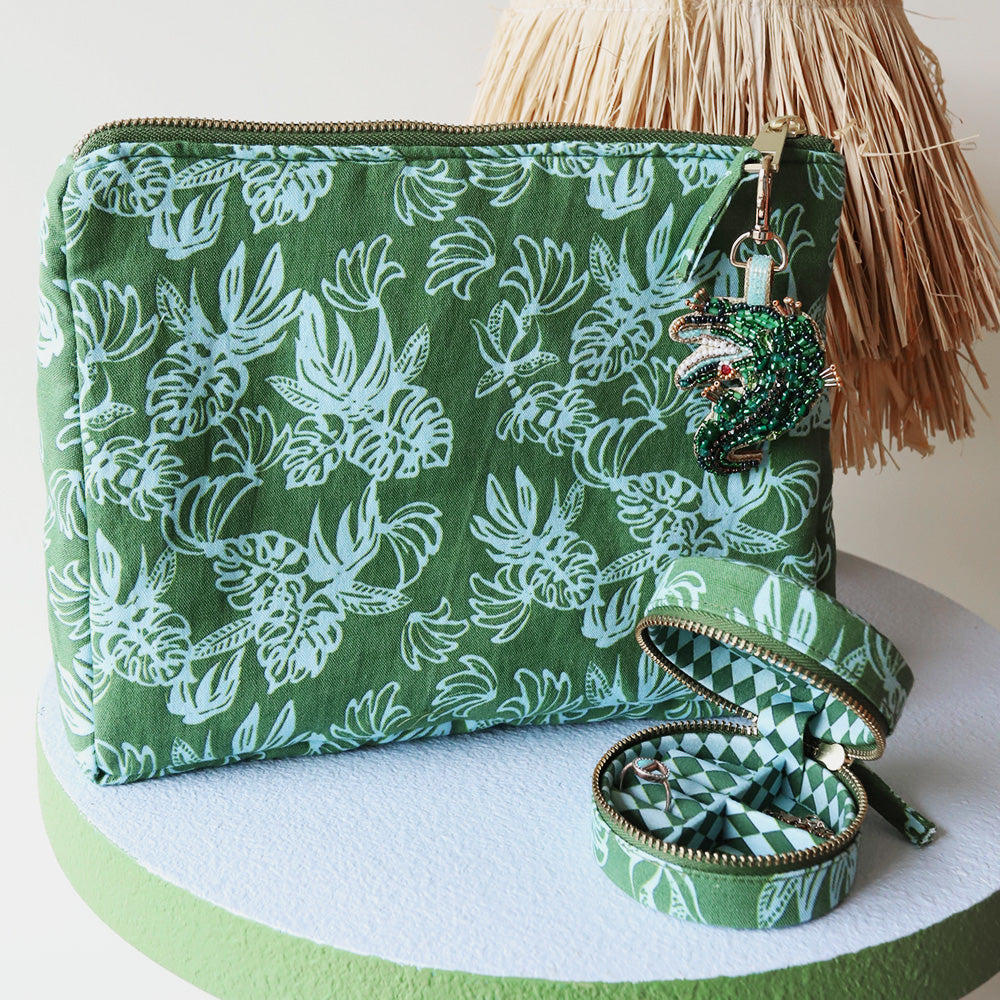 Green patterned cosmetic pouch with a decorative charm and mini linen jewellery box on a white surface