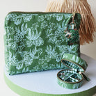Green patterned cosmetic pouch with a decorative charm and mini linen jewellery box on a white surface