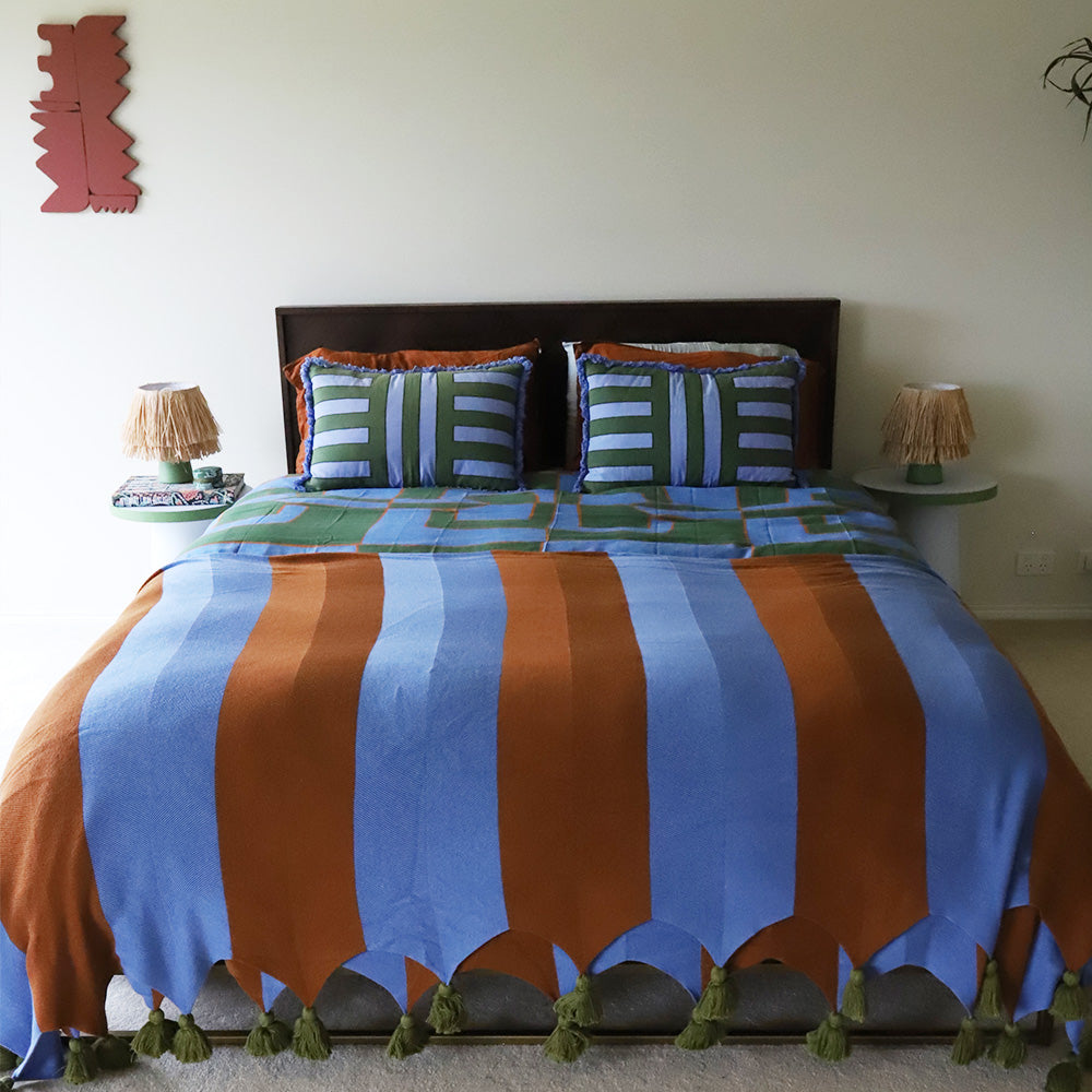 Bed with colorful striped throw blanket in brown and blue in a room setting
