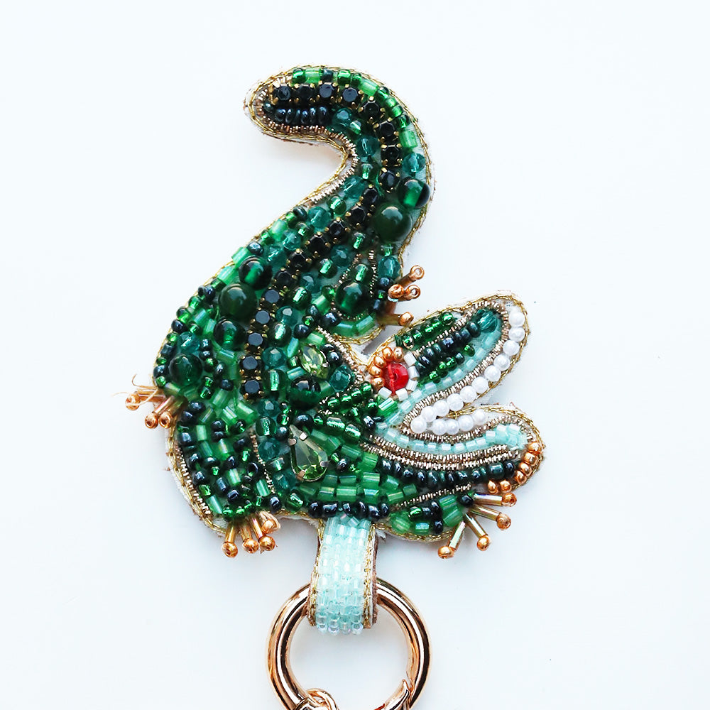 Decorative keychain with green beaded alligator design on a white background