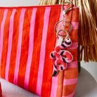 Red and pink striped pouch with a decorative snake beaded keychain on a white background