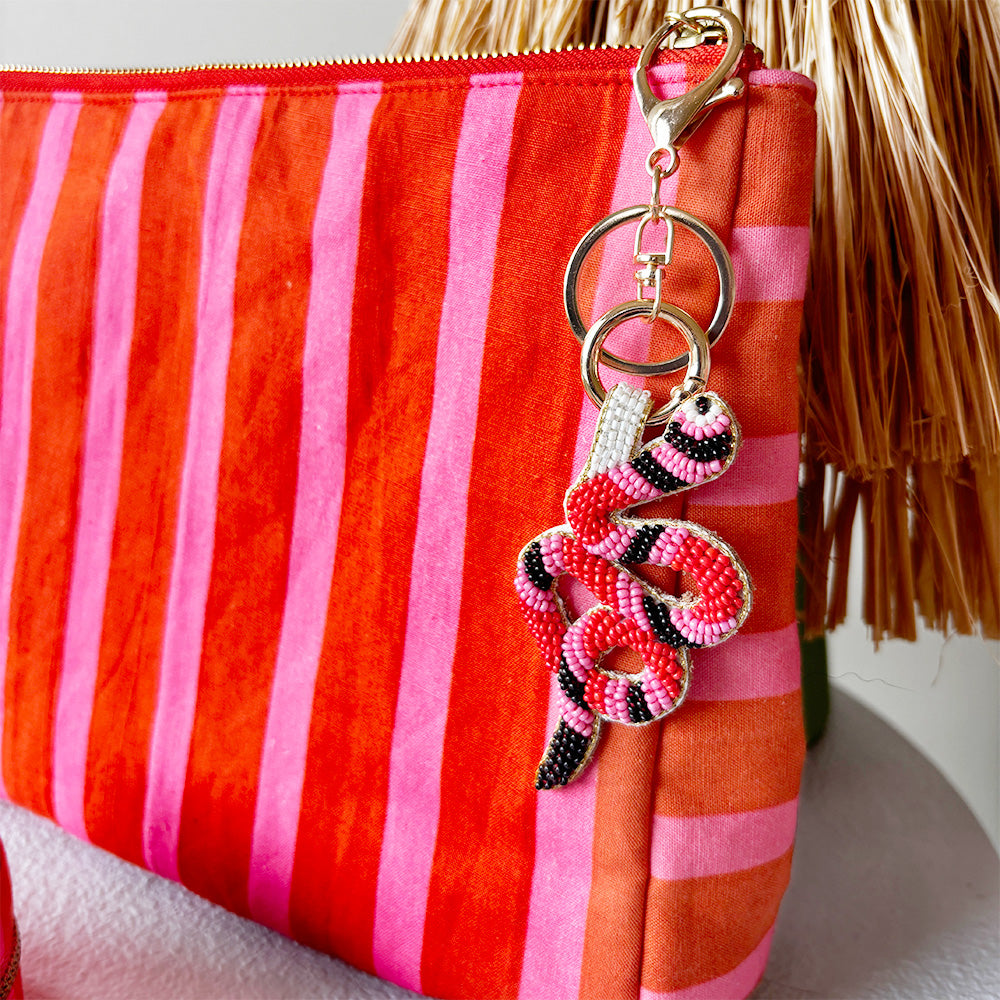 Red and pink striped pouch with a decorative keychain on a white background