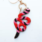 Snake-shaped keychain with red, pink, and black beads on a white background